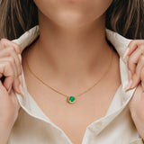 Woman wearing stunning bezel set solitaire necklace with colombian green emerald gemstone by Pel & Co custom emerald jewelry