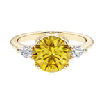 A 14k yellow gold three stone round engagement ring with a brilliant round yellow canary diamond looking yellow sapphire center diamond and two round side stones.
