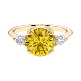 A 14k yellow gold three stone round engagement ring with a brilliant round yellow canary diamond looking yellow sapphire center diamond and two round side stones.