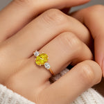 Hand adorned with oval 3 stone diamond ring in yellow gold.