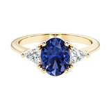 Oval cut three stone diamond engagement ring with romantic charm with blue gemstone center 14k yellow gold