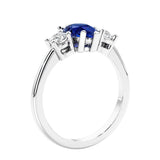 3 stone diamond engagement ring with pear shaped center in white gold featuring blue sapphire.