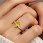 Woman wearing pear shaped three stone engagement ring with romantic flair.
