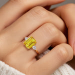 Woman wearing emerald cut three stone engagement ring with bold lines.