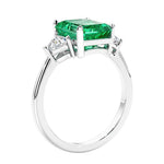 3 stone emerald cut diamond ring in modern gold setting with green gemstone center.