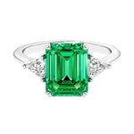 Three stone emerald cut engagement ring for timeless elegance featuring green gemstone and diamonds.