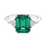 Three stone emerald cut engagement ring for timeless elegance featuring green gemstone and diamonds.