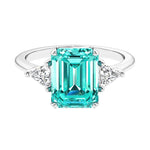 Three stone emerald cut engagement ring for timeless elegance featuring green gemstone and diamonds.