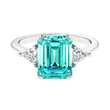 Three stone emerald cut engagement ring for timeless elegance featuring green gemstone and diamonds.