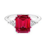 Three stone emerald cut engagement ring for timeless elegance featuring red gemstone and diamonds.