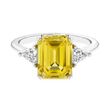 Three stone emerald cut engagement ring for timeless elegance featuring yellow gemstone and diamonds.