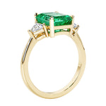 Emerald cut 3 diamond ring representing past, present, and future featuring green gemstone center.