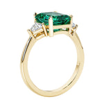 Emerald cut 3 diamond ring representing past, present, and future featuring green gemstone center.