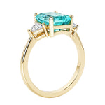 Emerald cut 3 diamond ring representing past, present, and future featuring green gemstone center.