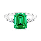 Three stone emerald cut engagement ring for timeless elegance featuring green gemstone and diamonds.