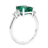 3 stone emerald cut diamond ring in modern gold setting with green gemstone center.