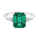 Three stone emerald cut engagement ring for timeless elegance featuring green gemstone and diamonds.