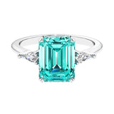 Three stone emerald cut engagement ring for timeless elegance featuring green gemstone and diamonds.