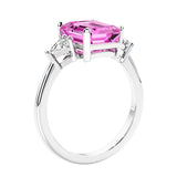 3 stone emerald cut diamond ring in modern gold setting with pink gemstone center.