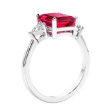 3 stone emerald cut diamond ring in modern gold setting with red gemstone center.