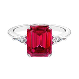 Three stone emerald cut engagement ring for timeless elegance featuring red gemstone and diamonds.