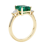 Emerald cut 3 diamond ring representing past, present, and future featuring green gemstone center.