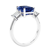 3 stone emerald cut diamond ring in modern gold setting with blue gemstone center.