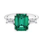Three stone emerald cut engagement ring for timeless elegance featuring green gemstone and diamonds.