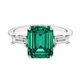 Three stone emerald cut engagement ring for timeless elegance featuring green gemstone and diamonds.