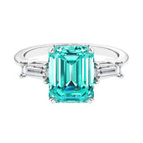 Three stone emerald cut engagement ring for timeless elegance featuring green gemstone and diamonds.