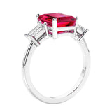 3 stone emerald cut diamond ring in modern gold setting with red gemstone center.