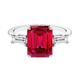 Three stone emerald cut engagement ring for timeless elegance featuring red gemstone and diamonds.