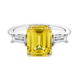Three stone emerald cut engagement ring for timeless elegance featuring yellow gemstone and diamonds.