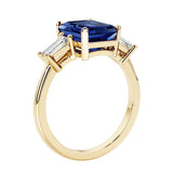 Emerald cut 3 diamond ring representing past, present, and future featuring blue gemstone center.