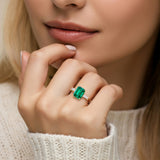 Woman wearing emerald cut three stone engagement ring with bold lines.
