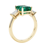 Emerald cut 3 diamond ring representing past, present, and future featuring green gemstone center.