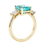 Emerald cut 3 diamond ring representing past, present, and future featuring green gemstone center.
