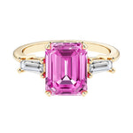 Emerald cut 3 stone engagement ring with pink gemstone and diamond accents.