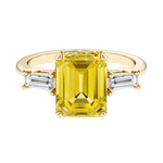 Emerald cut 3 stone engagement ring with yellow gemstone and diamond accents.