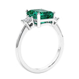 3 stone emerald cut diamond ring in modern gold setting with green gemstone center.