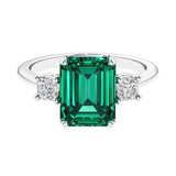 Three stone emerald cut engagement ring for timeless elegance featuring green gemstone and diamonds.