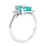 3 stone emerald cut diamond ring in modern gold setting with green gemstone center.