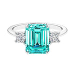 Three stone emerald cut engagement ring for timeless elegance featuring green gemstone and diamonds.
