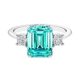Three stone emerald cut engagement ring for timeless elegance featuring green gemstone and diamonds.
