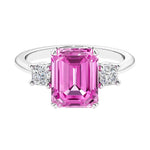 Three stone emerald cut engagement ring for timeless elegance featuring pink gemstone and diamonds.