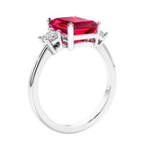 3 stone emerald cut diamond ring in modern gold setting with red gemstone center.