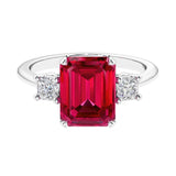 Three stone emerald cut engagement ring for timeless elegance featuring red gemstone and diamonds.