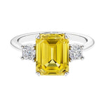 Three stone emerald cut engagement ring for timeless elegance featuring yellow gemstone and diamonds.