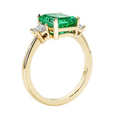 Emerald cut 3 diamond ring representing past, present, and future featuring green gemstone center.