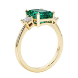Emerald cut 3 diamond ring representing past, present, and future featuring green gemstone center.